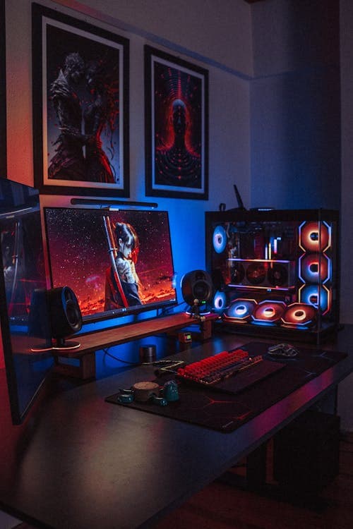 A dual-monitor RGB gaming desk setup with a custom PC and backlit keyboard — a capable 1080p gaming setup is achievable for $650–750 with new parts, or $500–650 with a used GPU