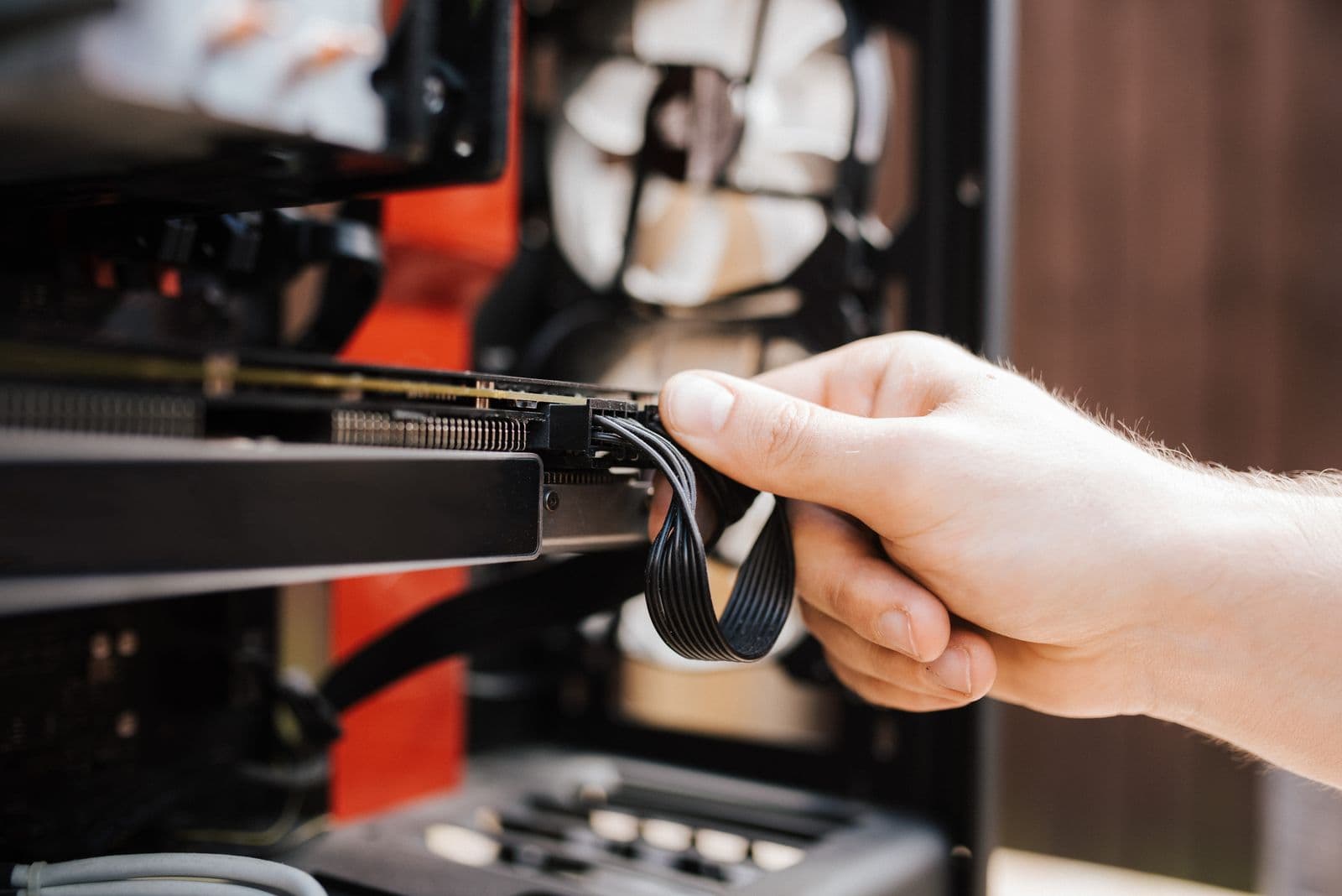 A hand connecting a power cable to a graphics card