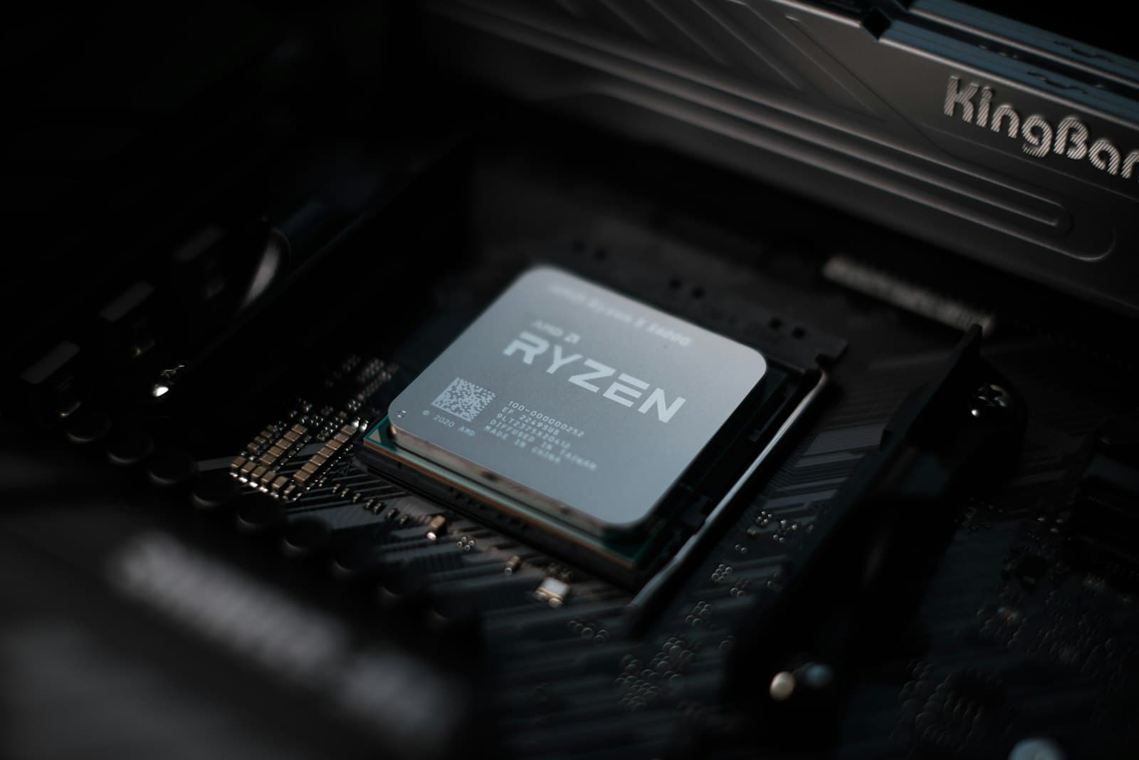 A CPU being seated into a motherboard socket, showing the AM5 and LGA1851 socket pin layouts used in modern gaming builds