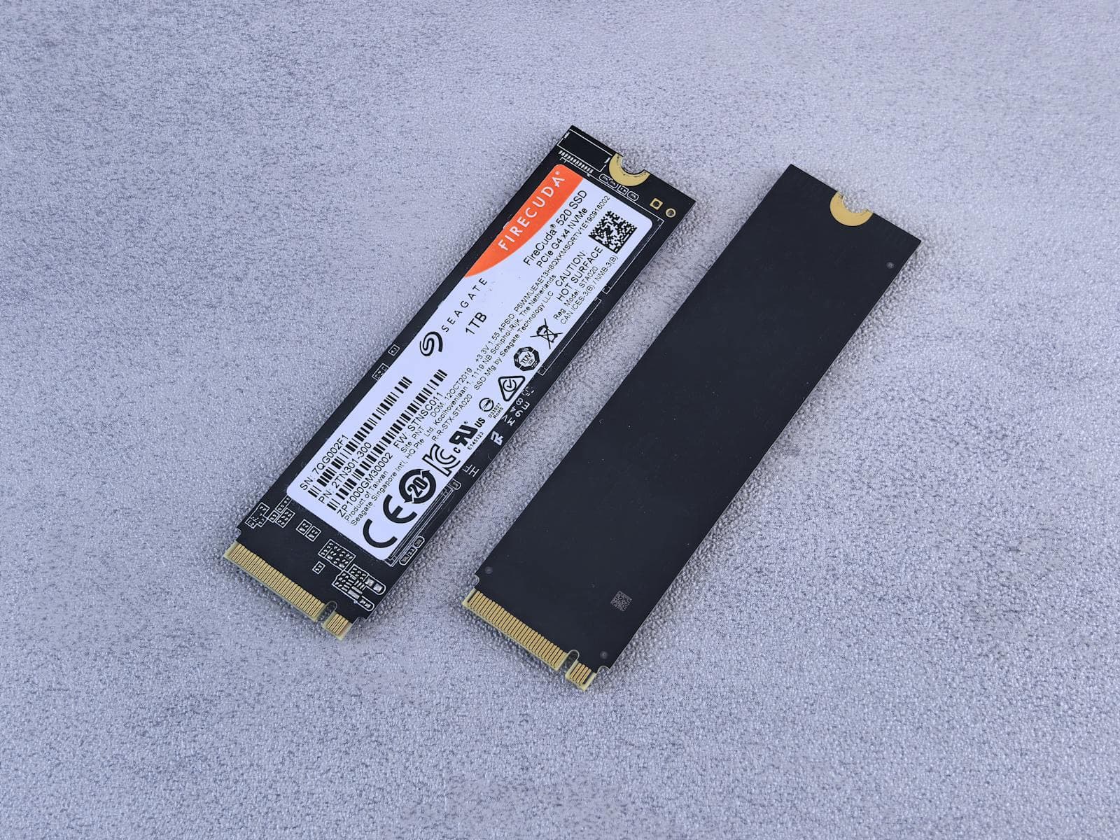 Two NVMe M.2 SSDs side by side on a neutral surface, showing the compact stick form factor of modern gaming storage drives