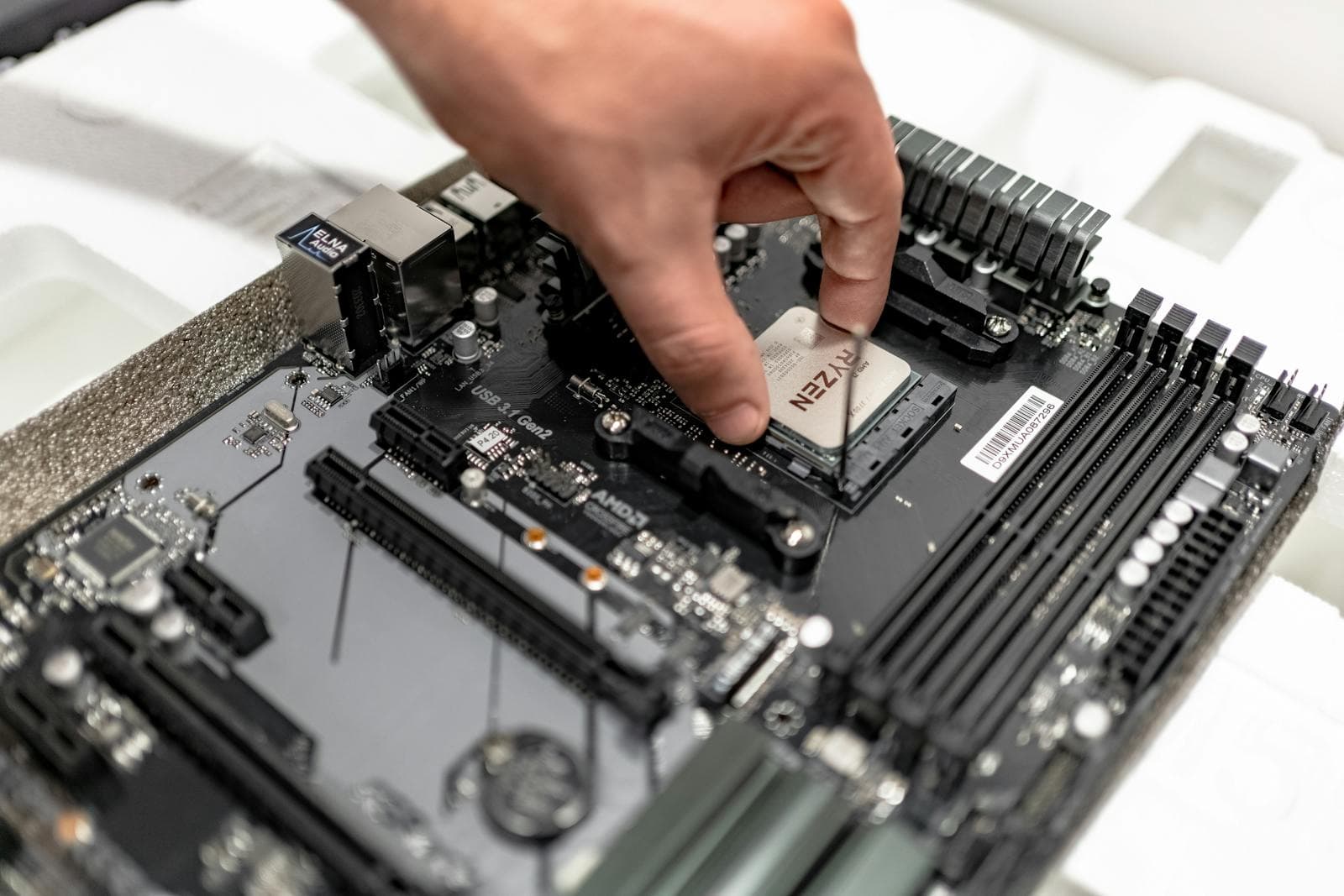 A hand installing a CPU into a motherboard socket, showing correct alignment of the socket lever and CPU orientation markers