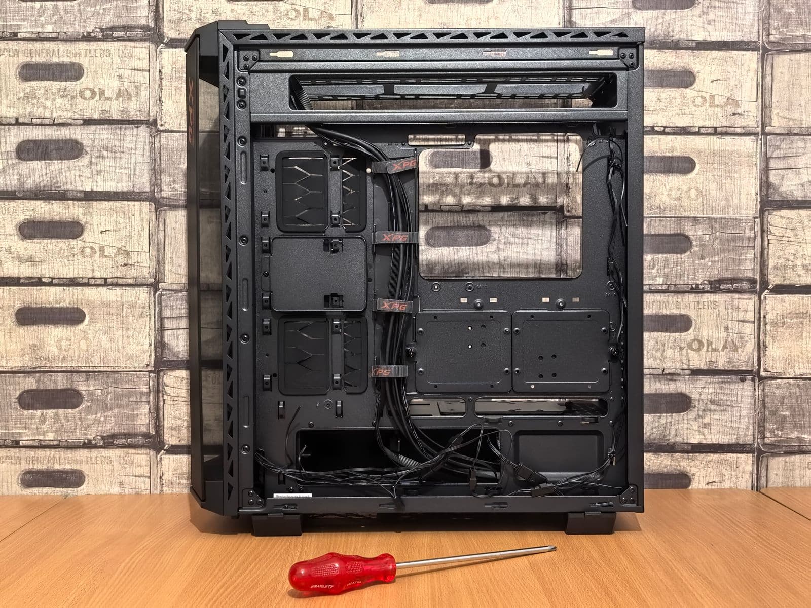 Open black PC case on a wooden desk with a Phillips screwdriver placed beside it, ready for PC assembly