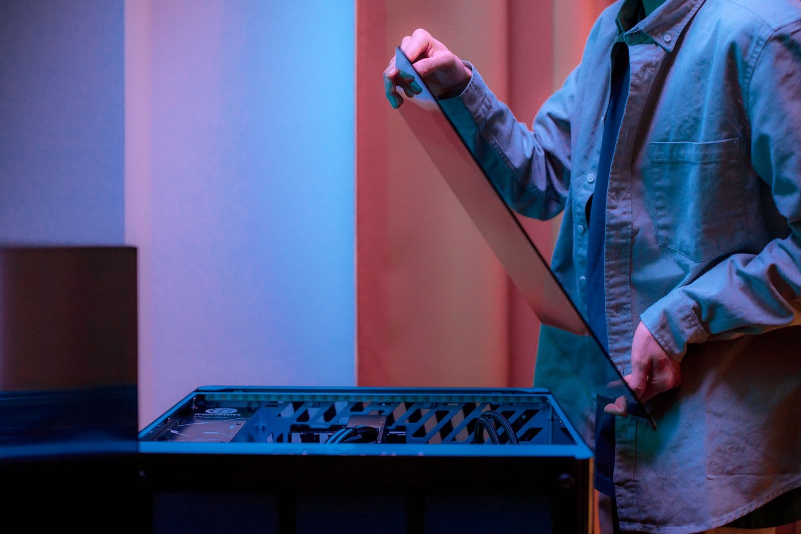 A person installing a tempered glass side panel onto a gaming PC case