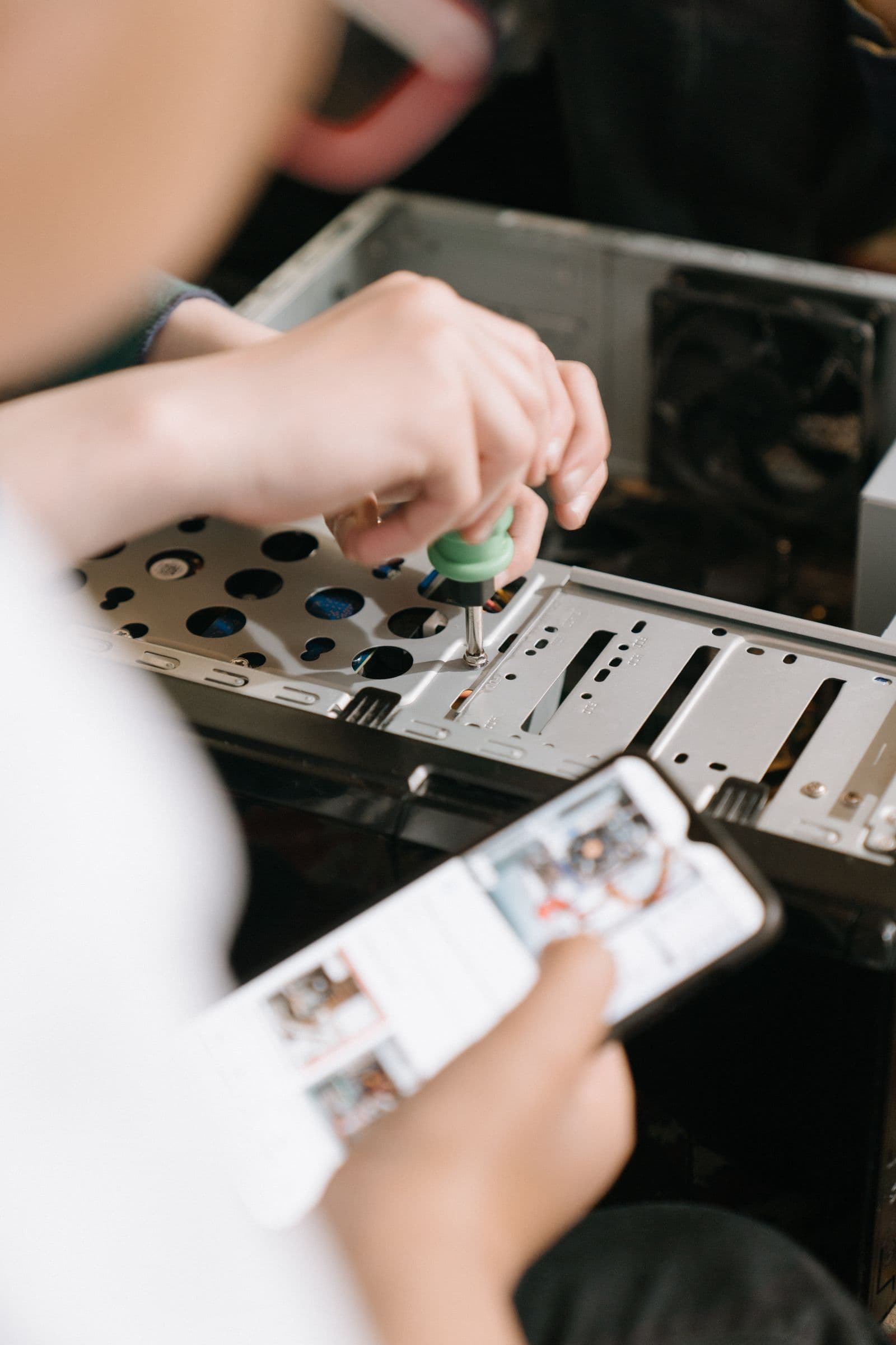 Hands using a screwdriver to work on computer hardware