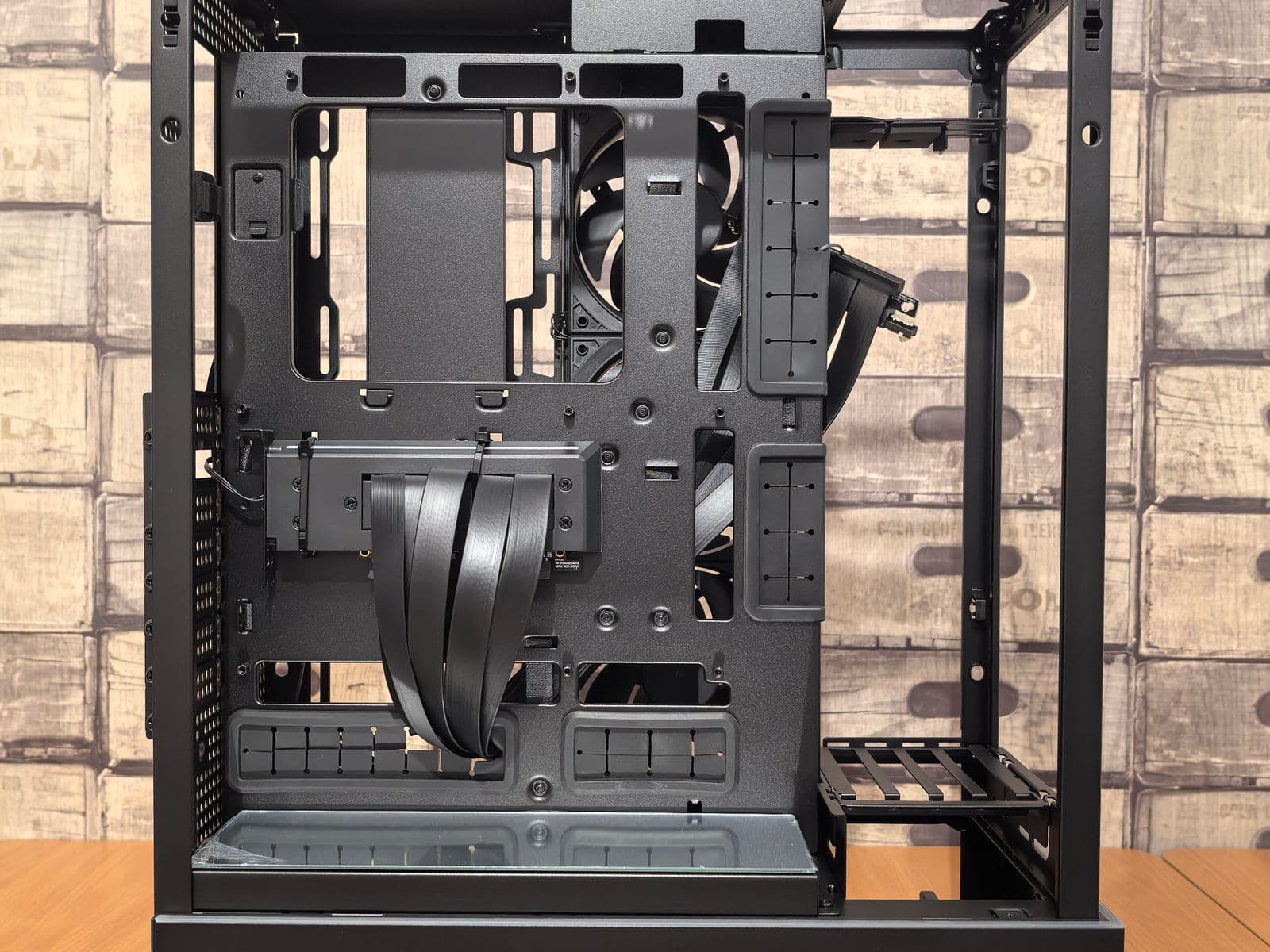 Interior of an open PC case showing the component layout including exposed motherboard M.2 slots for SSD installation in a gaming build