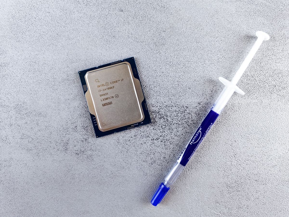 Close-up of an Intel CPU next to a syringe of fresh thermal paste